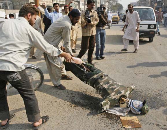 Protester sprinkles petrol on an effigy of General  Musharraf 