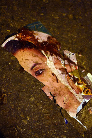 A torn poster of Benazir Bhutto lies in the street at the site of the explosion