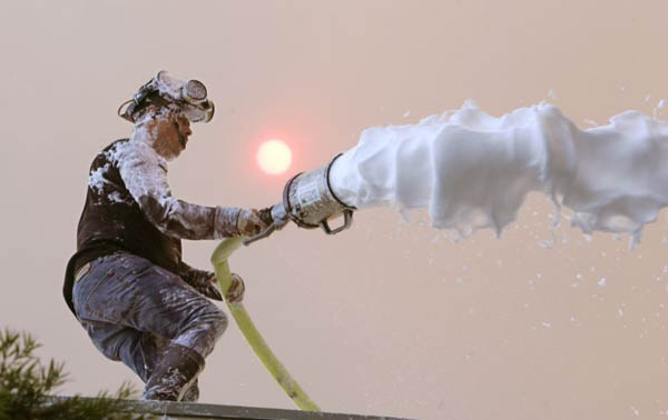 Geronimo Ruiz foams a roof where a wildfire driven by powerful Santa Ana winds threatened a university and forced the evacuation of hundreds of homes
