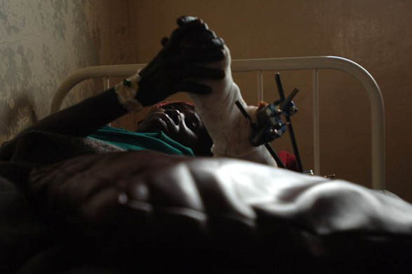 A woman with bullet wounds lies on a hospital bed