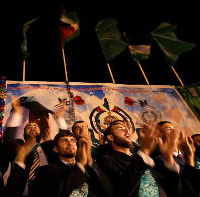 Palestinian grooms applaud during a mass wedding