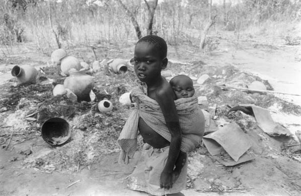 Two orphaned children wander through the ruins of a deserted village