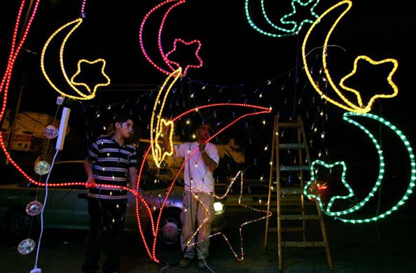 Men decorate their shop with festive lights