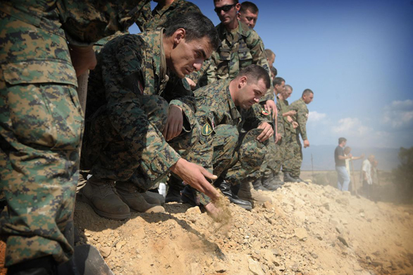 Georgian soldiers throw earth onto the mass grave for unknown soldiers