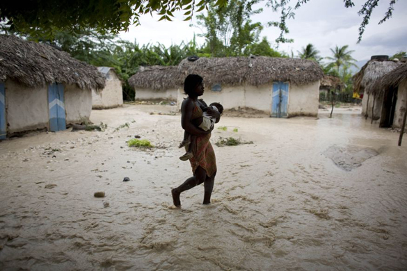 A woman carries a child through flooded roads caused by Tropical Storm Gustav