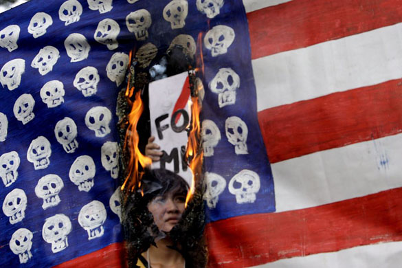 Manila, Philippines: A student is seen through a  burning US flag, during a protest outside the US embassy  