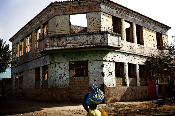 Kuito , Angola: A boy carries a bag in front of a building which was destroyed during the country's 27-year civil war