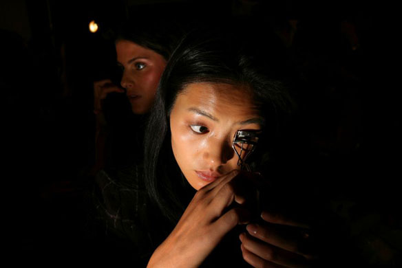 A model works on her eye lashes before the Anna Sui show during Fashion Week