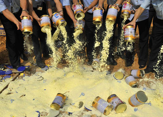 UnassignedLocal officials empty tainted milk power packets at a rubbish dump  