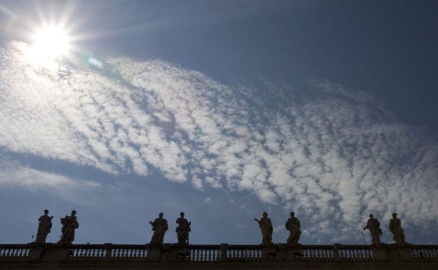Vatican City: Statues on the roof  St Peter's Basilica are silhouetted under clouds 