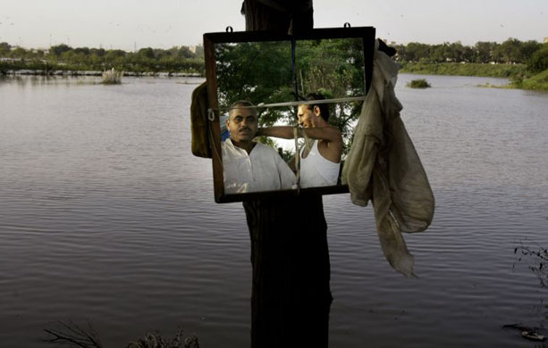 A barber gives a head massage to a customer beside the Yamuna river, India 