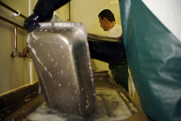 Derek, kitchen orderly (pot washer) cleaning up a stale lasagne dish. £5.40 per week