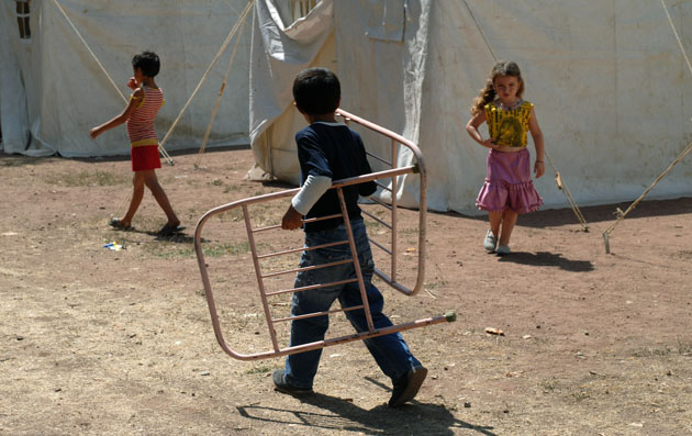 A young boy carries bedposts to build a makeshift camp bed 