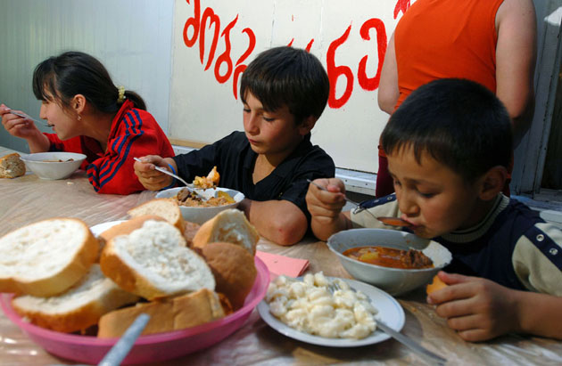 Children eat a communal dinner at a refugee camp in Tokhliauri