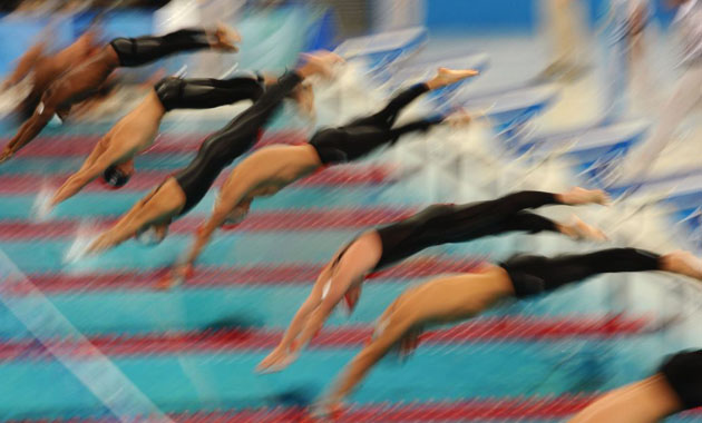 Athletes dive during the men's 400m individual medley swimming heat at the National Aquatics Center