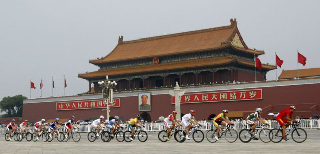 Competitors cycle past the portrait of Chinese leader Mao Zedong in Tiananmen Square during the men's road race cycling compeition in Beijing