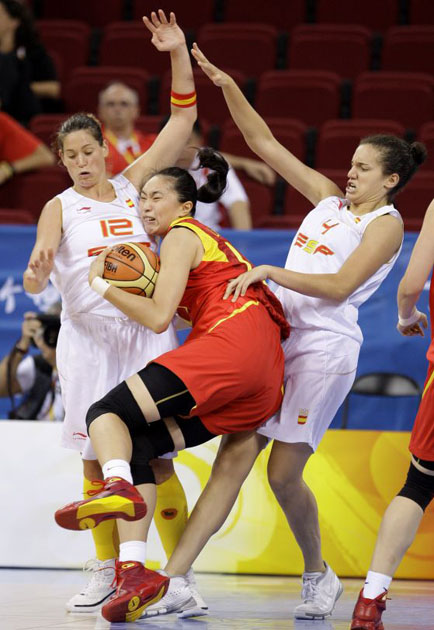 China's Liu Dan, center, runs into Spain's Anna Montanana (12), left, and Laura Nicholls, right, during the first quarter of their women's preliminary basketball game in Beijing