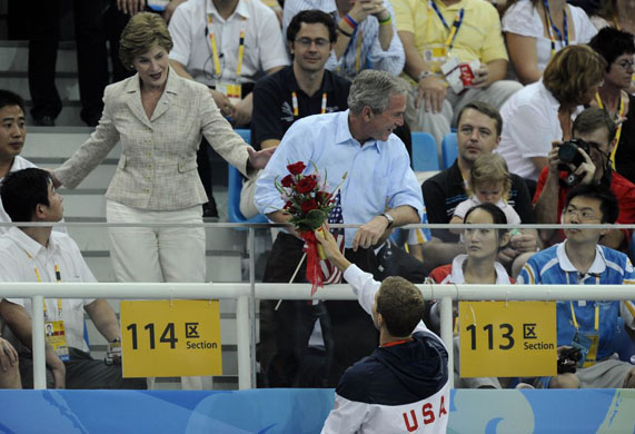 George W Bush gets flowers for his wife Laura from Larson Jensen after his bronze medal presentation in the mens 400m freestyle