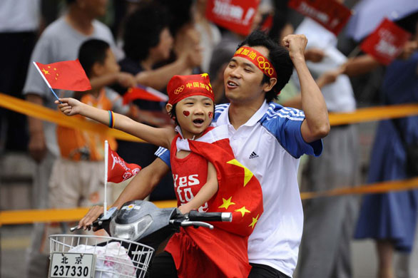 Father and daughter cheer on the runners while speeding next to them on a moped