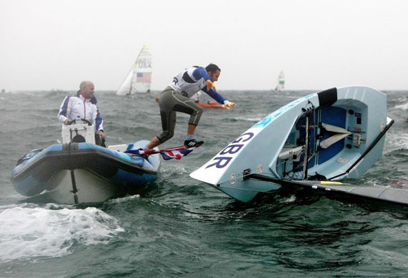 Ben Ainslie leaps back to his capsized boat after celebrating his Gold Medal