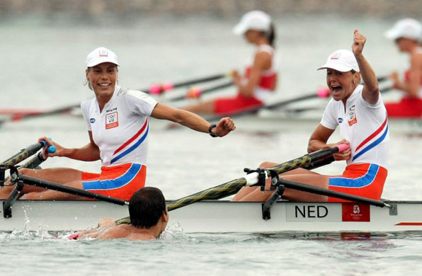 A swimming supporter congratulates Netherlands Marit van Eupen (L) and Kirsten van der Kolk after winning the Gold Medal 
