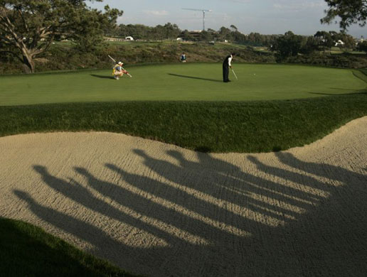 Caddie Matt Achatz watches as Rocco Mediate puts at the US Open 
