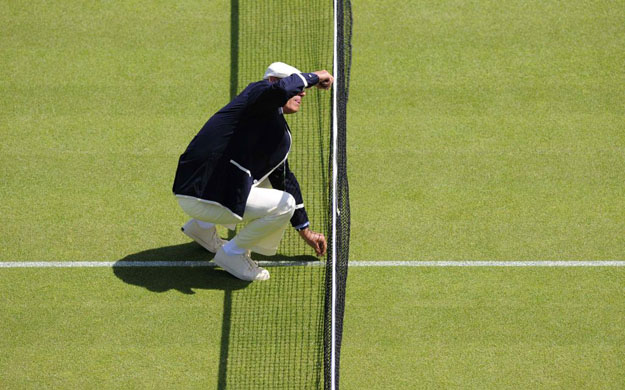 An umpire measuring the net height