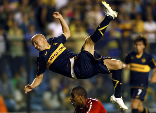 Luciano Figueroa of Boca Juniors falls over Alvaro of Brazil's Internacional during their second-leg quarter-final Copa Sudamericana match