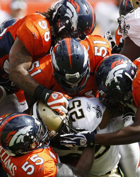 New Orleans Saints running back Reggie Bush is tackled by the Denver Broncos