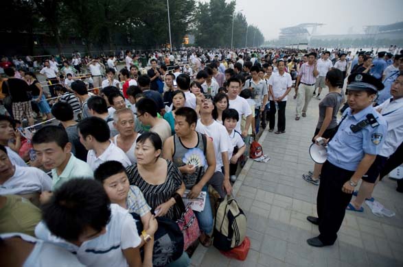 A security guard watches the queue for Olympic tickets