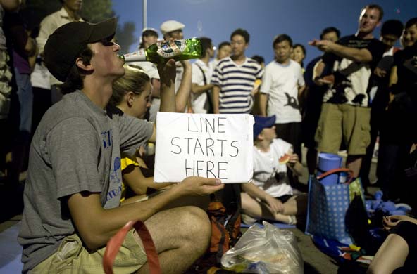 A man holds up a sign saying 'Line starts here'