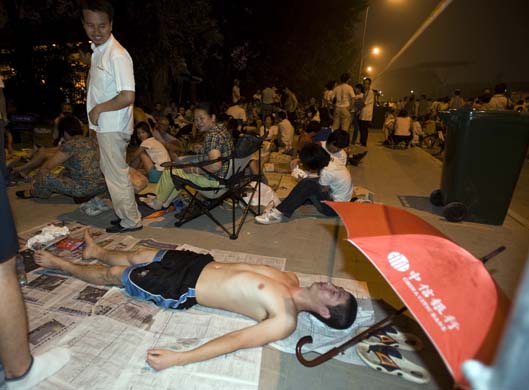 A man lies on a bed of newspaper in the queue