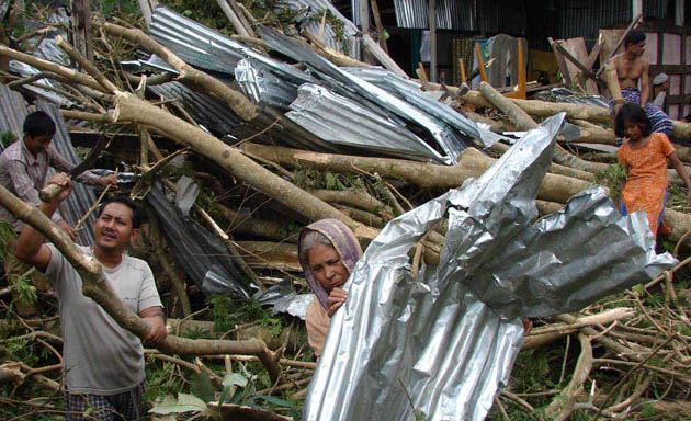 A woman in Barishal picks up what is left of her roof in the aftermath of cyclone Sidr