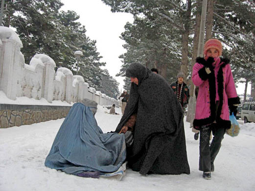 A woman begs for alms on a snow covered road
