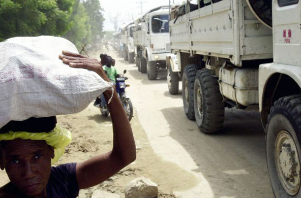 Port-au-Prince, Haiti: People walk by UN peacekeeping trucks as aid is delivered to flood victims in the devastated city of Gonaives