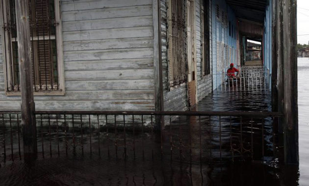 Batabano, Cuba: A resident sits outside his flooded house