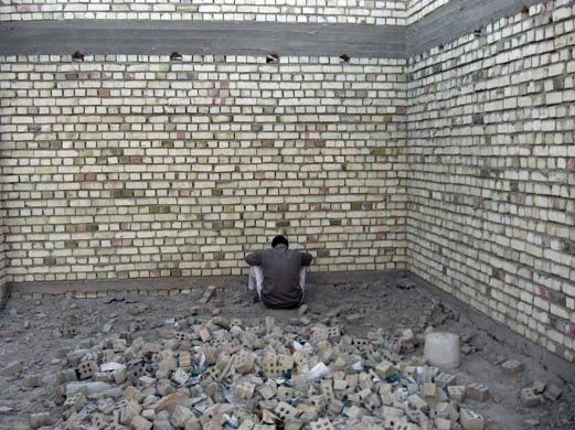 A suspect is forced to sit facing a wall and await questioning by soldiers who had just discovered him near a secret bomb-making factory in an unfinished house in al-Hadar