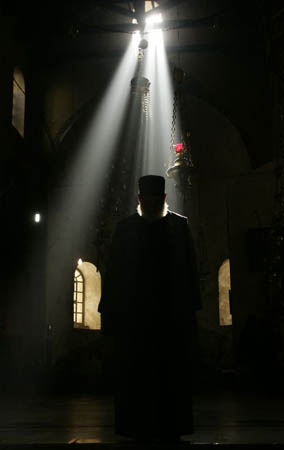 A priest walks towards the Grotto at the Church of the Nativity