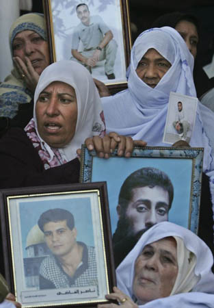 Palestinian women hold pictures of prisoners held in Israeli jails during a weekly protest calling for their release