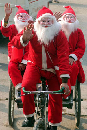 Men dressed as Santa Claus sit on a cycle-rickshaw