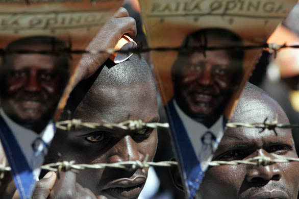 Supporters of the Orange Democratic Movement stand next to posters of the leader, Raila Odinga