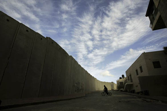 A Palestinian boy rides his bicycle next to a section of Israel's barrier separating the outskirts of Jerusalem from the West Bank