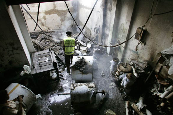 A policeman investigates the burned printing press of Sunday Leader newspaper group