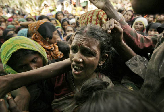 A woman shouts in pain as others push towards the entrance of a relief centre