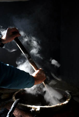 A man stirs a plum mash inside a small distilling installation