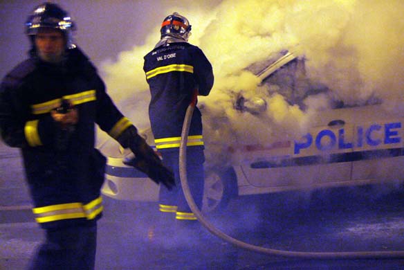 Firemen put out a police car on fire