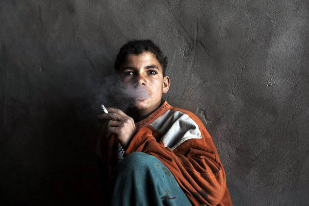 Cairo, Egypt: Ali Andak, a 15-year old worker at the Amal Misr Brick factory, smokes a cigarette during a lunch break