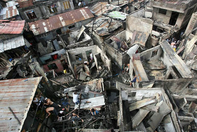 Paranaque City, Philippines: Fire victims try to salvage useful items among the debris after a fire razed the houses of some 200 families