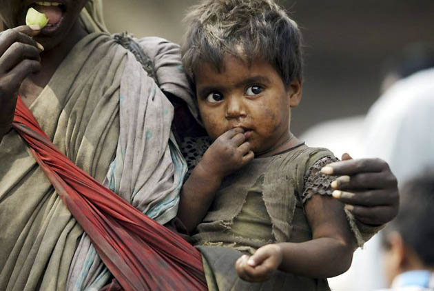 Jammu, India: A street beggar carries her child