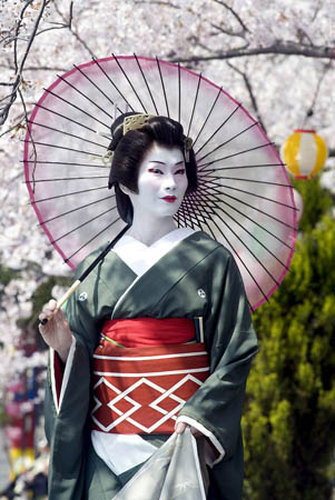 Atami, Japan: A geisha walks under a canopy of cherry blossoms